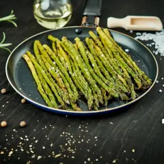 Asparagi in padella, conditi con sale e pepe, pronti per essere gustati.