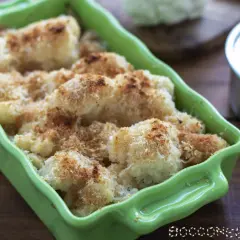 Cavolfiore al forno con pangrattato e formaggio, dorato e croccante, servito in una teglia verde brillante.