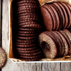 Una scatola piena di deliziosi biscotti al cacao, alcuni impilati in modo ordinato, altri con un bordo dorato croccante.