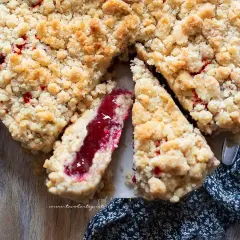 Una deliziosa sbriciolata alla marmellata, con la sua crosta dorata e il ripieno rosso brillante, pronta per essere gustata.