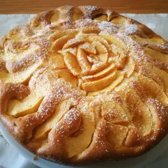 Deliziosa torta di mele senza glutine, con mele disposte a rosa al centro e spolverata di zucchero a velo.