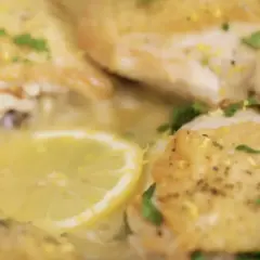 Succulento pollo al limone, dorato e profumato, con fette di limone e prezzemolo fresco.
