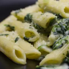 Penne cremose con spinaci freschi e parmigiano grattugiato, un piatto semplice e gustoso.