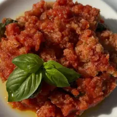 Piatto di pappa al pomodoro, un classico toscano, guarnito con foglie di basilico fresco.