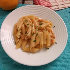 Piatto di pasta al salmone senza panna, guarnita con prezzemolo fresco. Un'opzione leggera e gustosa.