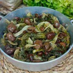 Scarola in padella con olive e uvetta, un contorno saporito e colorato, pronto per essere gustato.