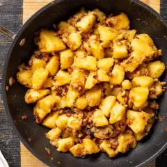 Patate in tecia dorate e croccanti, condite con pancetta e cipolla, pronte per essere gustate.
