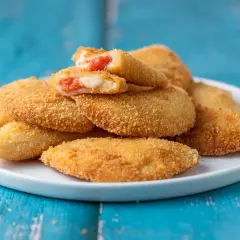 Sofficini fatti in casa dorati e croccanti, ripieni di pomodoro e mozzarella filante, serviti su un piatto bianco.