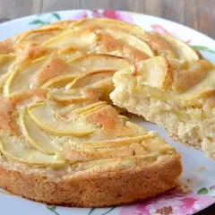 Una fetta di torta di mele senza uova, con mele a fette disposte a spirale sulla superficie dorata.