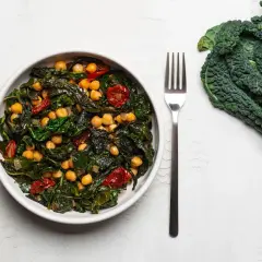 Piatto invitante con cavolo nero, ceci e pomodorini secchi, un'idea per una cavolo nero ricetta sana e gustosa.