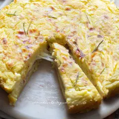 Torta salata con patate, filante e dorata, guarnita con rosmarino. Perfetta per un pranzo o una cena gustosa.