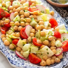 Insalata di ceci fresca e colorata con pomodorini, cetrioli e ravanelli, condita con erbe aromatiche.