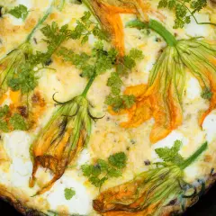 Frittata dorata con fiori di zucca e prezzemolo fresco, un piatto primaverile invitante.