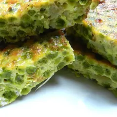 Fette di frittata di piselli, dorata e soffice, con piselli verdi ben visibili nell'uovo.