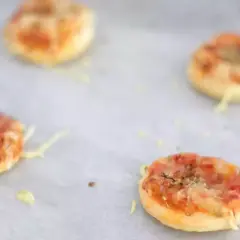 Quattro pizzette di pasta sfoglia appena sfornate, dorate e filanti, pronte per essere gustate.