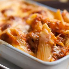 Un invitante piatto di pasta al forno, con penne ricoperte da un ricco sugo e formaggio filante, pronto per essere gustato.
