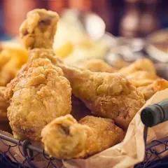 Cesto pieno di croccante petto di pollo impanato e patatine fritte dorate.