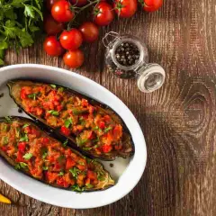 Melanzane a barchetta ripiene, pronte per essere gustate. Ingredienti freschi e un tocco di peperoncino giallo.