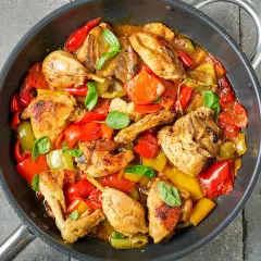 Pollo e peperoni in padella, un piatto colorato e saporito, con pezzi di pollo dorati e peperoni rossi e gialli cotti a puntino.