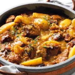 Un invitante spezzatino di manzo morbidissimo con patate, cotto lentamente in un ricco sugo e guarnito con prezzemolo fresco.