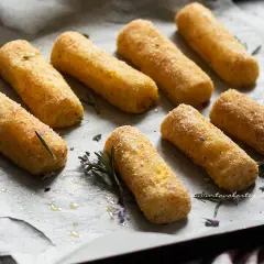Crocchette di patate al forno dorate e croccanti, pronte per essere gustate. Profumate con rosmarino fresco.