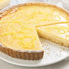 Una deliziosa crostata con crema pasticcera, guarnita con scorza di limone e spolverata di zucchero a velo.