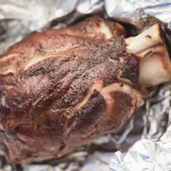 Stinco di maiale succulento, cotto alla perfezione e avvolto in carta stagnola, pronto per essere gustato.