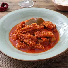 Un piatto fumante di trippa alla fiorentina, con la sua consistenza unica e il sugo rosso invitante, pronto per essere gustato.