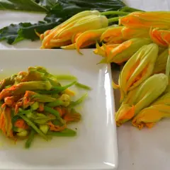 Fiori di zucca in padella, un piatto primaverile pronto da gustare. Accanto, fiori freschi in attesa di essere cucinati.