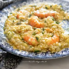 Risotto cremoso con zucchine e gamberetti, un piatto estivo da gustare.