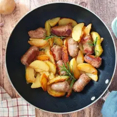 Salsiccia e patate in padella, dorate e profumate, con rametti di rosmarino. Un piatto rustico e invitante.