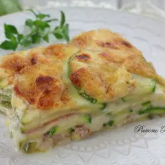 Fetta di lasagne di zucchine, stratificata con prosciutto e besciamella, gratinata al forno.