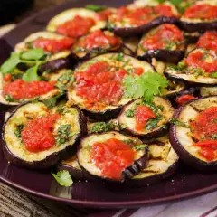 Fette di melanzane grigliate condite con salsa di pomodoro e basilico, un classico piatto di melanzane alla pizzaiola.