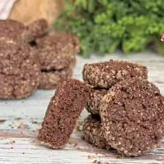 Biscotti al cioccolato rustici, ricoperti di zucchero grezzo, su un tavolo di legno. Uno spezzato rivela la consistenza friabile.