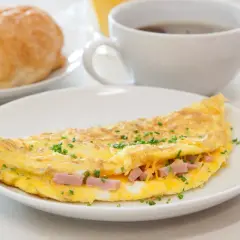 Deliziosa omelette con prosciutto e formaggio filante, guarnita con erba cipollina. Perfetta per una colazione o un brunch.