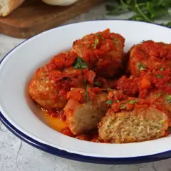 Polpette di pane succulente in salsa di pomodoro, guarnite con prezzemolo fresco. Un piatto casalingo che sa di tradizione.