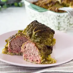 Involtini di verza con carne succulenta, uno tagliato a metà per mostrare il ripieno saporito.