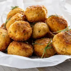 Un mucchio invitante di polpette in bianco, dorate e croccanti, guarnite con rosmarino fresco e sale grosso.