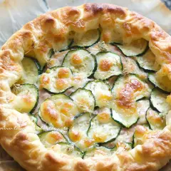 Torta salata con zucchine, formaggio filante e crosta dorata, pronta per essere gustata.