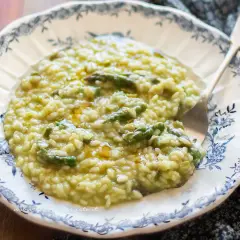 Un cremoso risotto con asparagi, servito in un piatto decorato. Un piatto primaverile invitante.