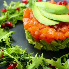 Tartare di salmone e avocado, guarnita con melagrana e insalatina fresca. Antipasti sfiziosi per stupire con gusto e colore.