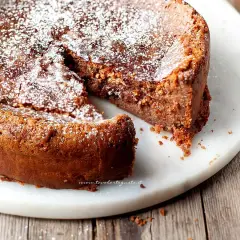 Una deliziosa torta al cioccolato al latte, cosparsa di zucchero a velo, con una fetta mancante che invita ad assaggiarla.