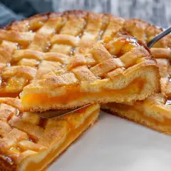 Deliziosa crostata senza glutine con ripieno di albicocche, una fetta sollevata da una paletta.