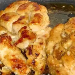 Succulento pollo in padella, dorato e saporito, con pezzetti di aglio che aggiungono un tocco in più.