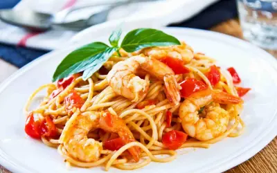 Un piatto invitante di spaghetti con gamberi succulenti e pomodorini freschi, guarnito con basilico.