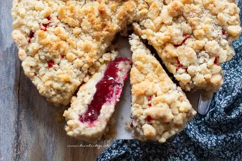 Una deliziosa sbriciolata alla marmellata, con la sua crosta dorata e il ripieno rosso brillante, pronta per essere gustata.