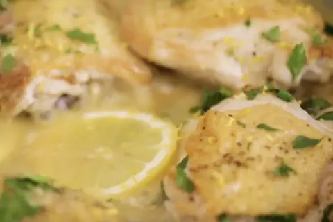 Succulento pollo al limone, dorato e profumato, con fette di limone e prezzemolo fresco.