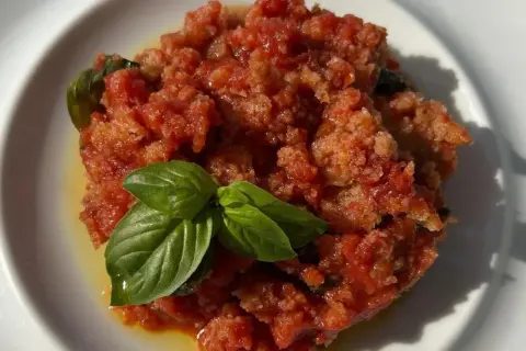 Piatto di pappa al pomodoro, un classico toscano, guarnito con foglie di basilico fresco.