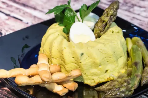 Delizioso flan di asparagi, guarnito con uovo sodo, asparagi freschi e grissini croccanti. Un piatto primaverile da gustare.
