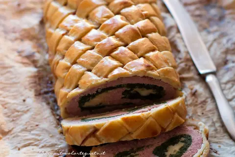 Un delizioso polpettone in crosta, con un ripieno di carne, spinaci e formaggio, pronto per essere affettato.